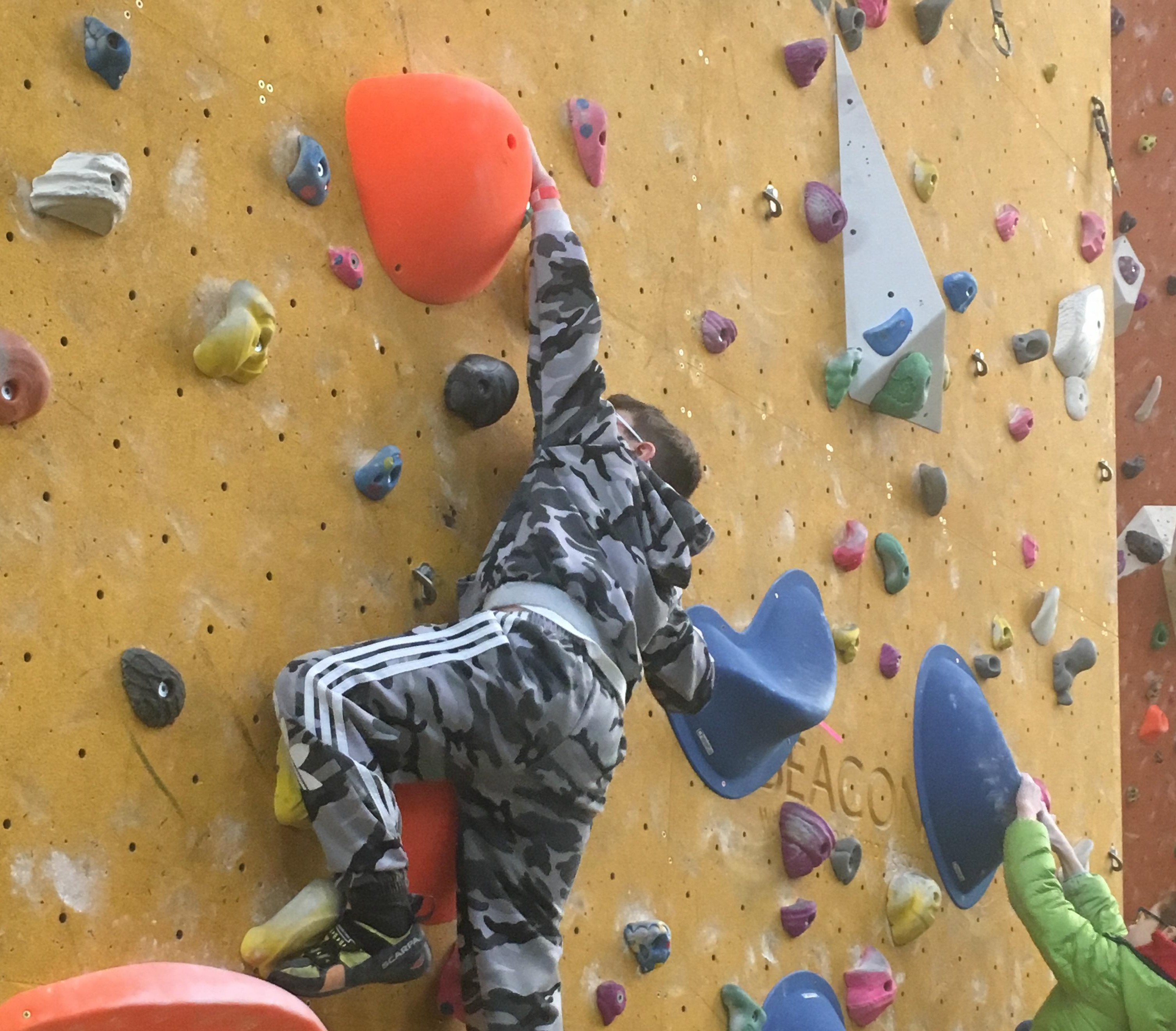 Oscar Preston climbing on slopers at a climbing wall